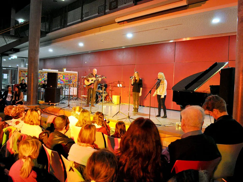 Band spielt vor der roten Wand, davor das Publikum.